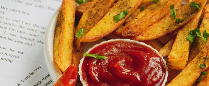 Een foto van een bord met frietjes, geserveerd met ketchup en wat kruiden